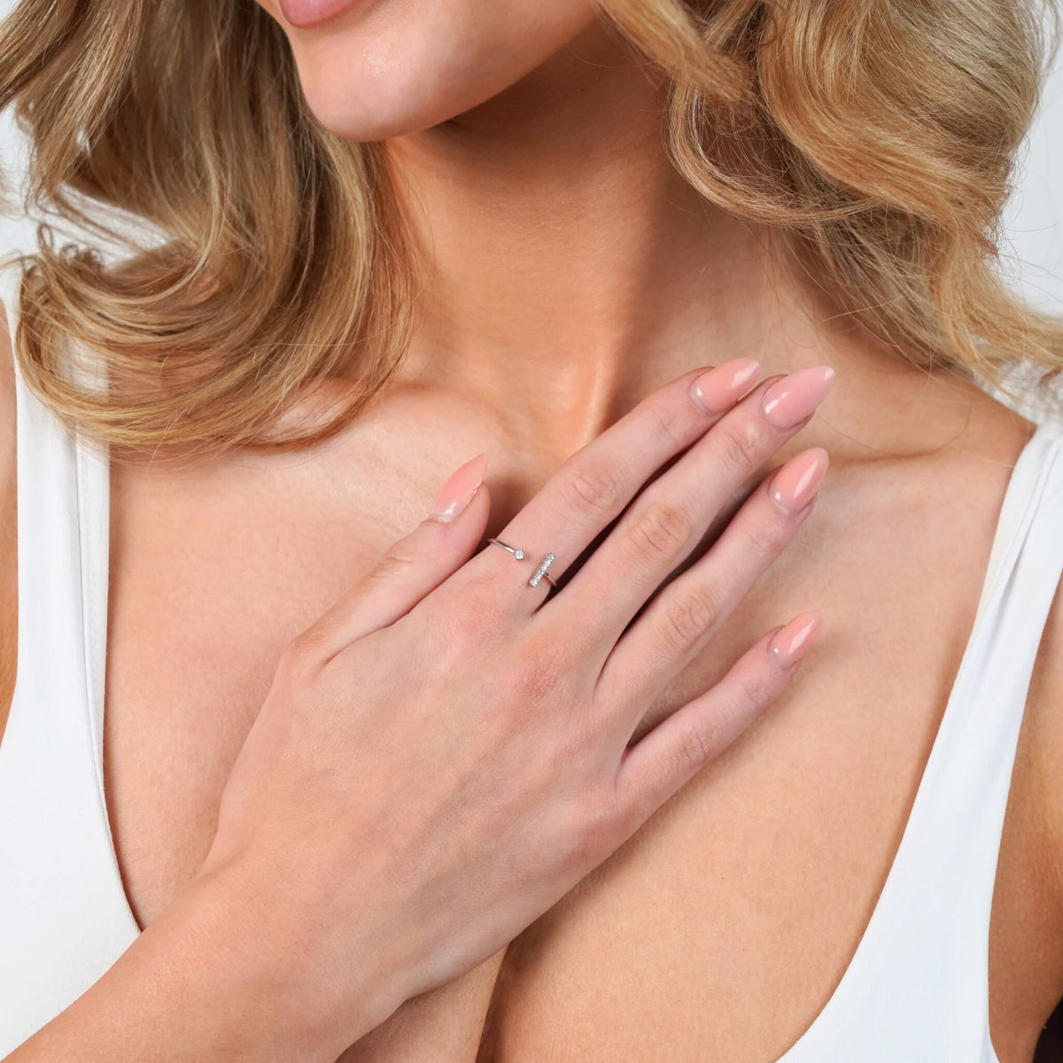 Silver bar and stone open ring worn on a hand resting on the chest